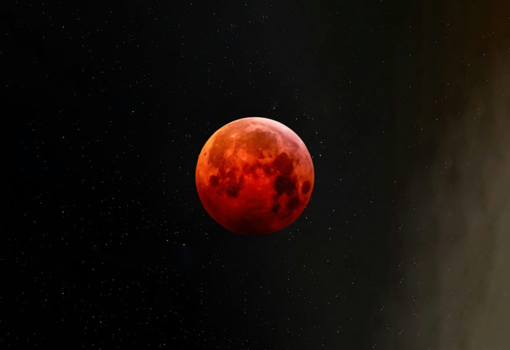 a red moon is seen in the night sky