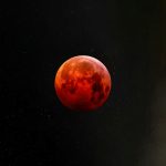 a red moon is seen in the night sky