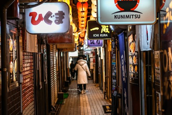 A person walks down a dimly lit asian alley.