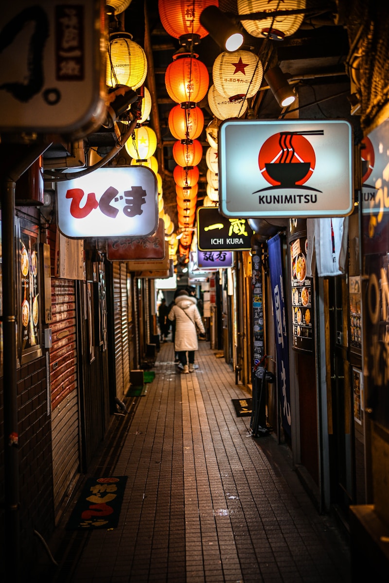 A person walks down a dimly lit asian alley.