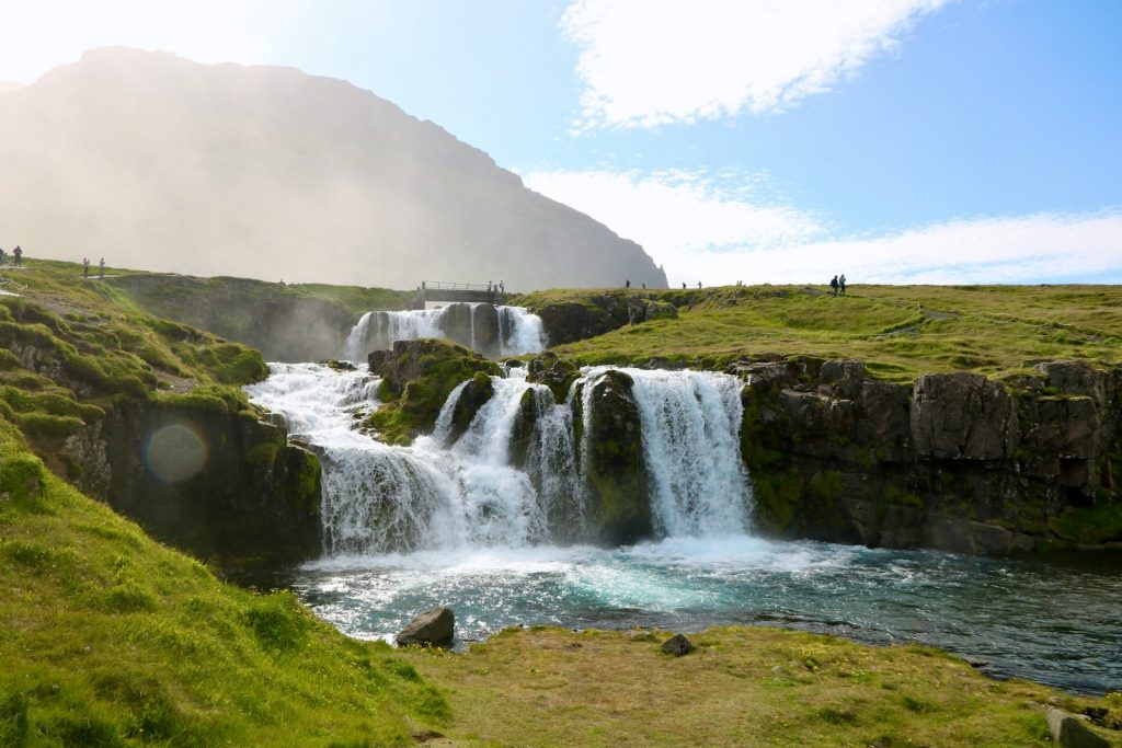 a group of people standing at the base of a waterfall