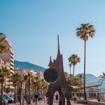 a statue of a dog in a plaza with palm trees