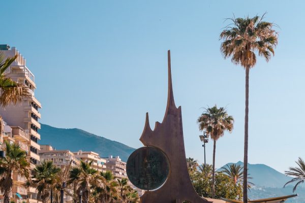 a statue of a dog in a plaza with palm trees