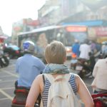 woman wearing backpack walking on road