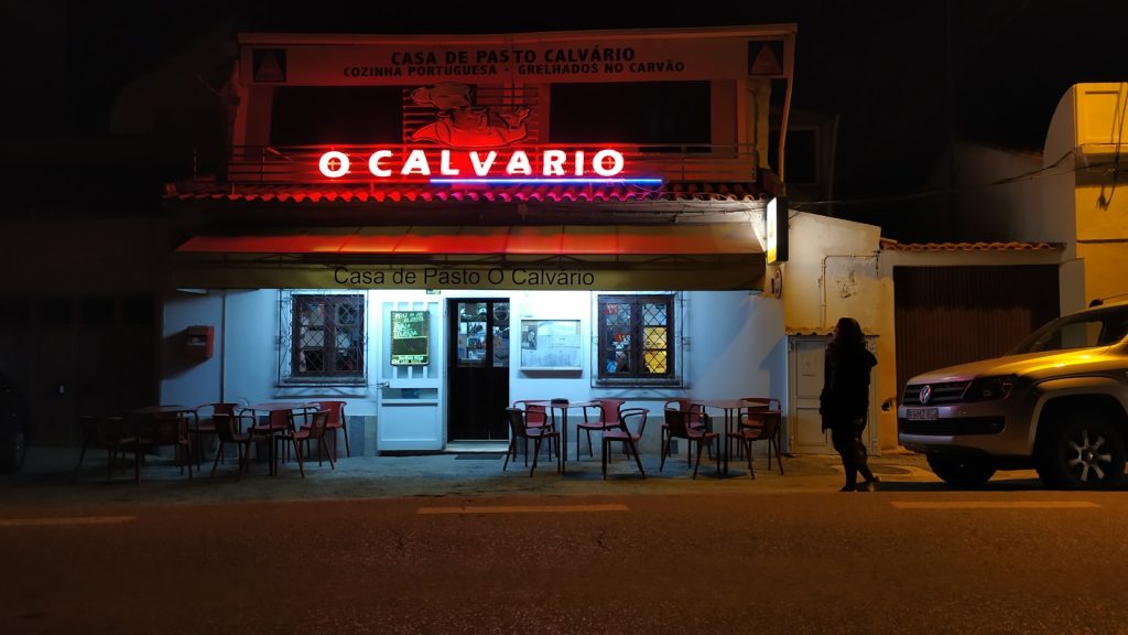 a person standing outside of a restaurant at night