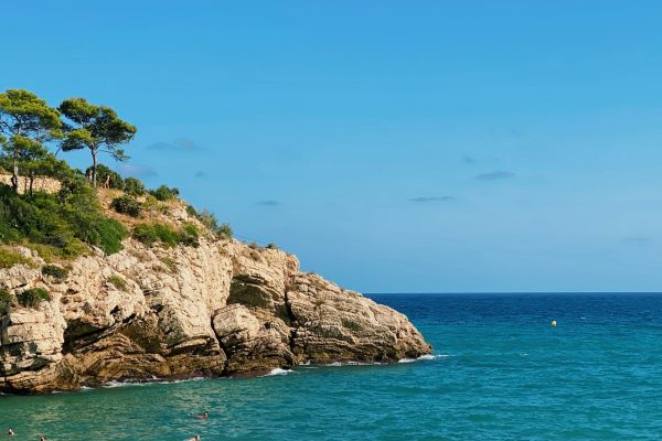 brown rocky mountain beside blue sea under blue sky during daytime