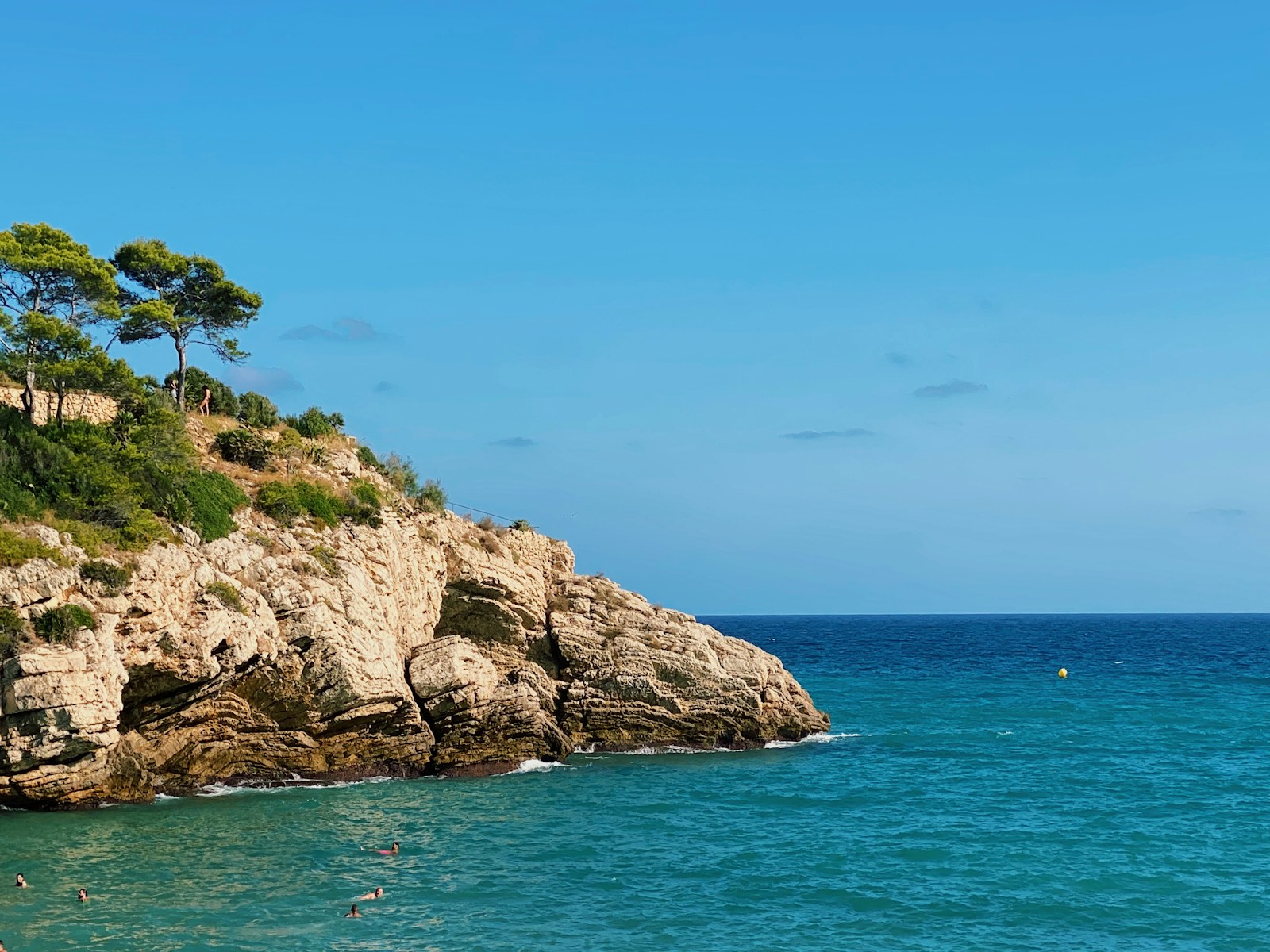 brown rocky mountain beside blue sea under blue sky during daytime