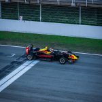 a red and yellow race car driving down a race track