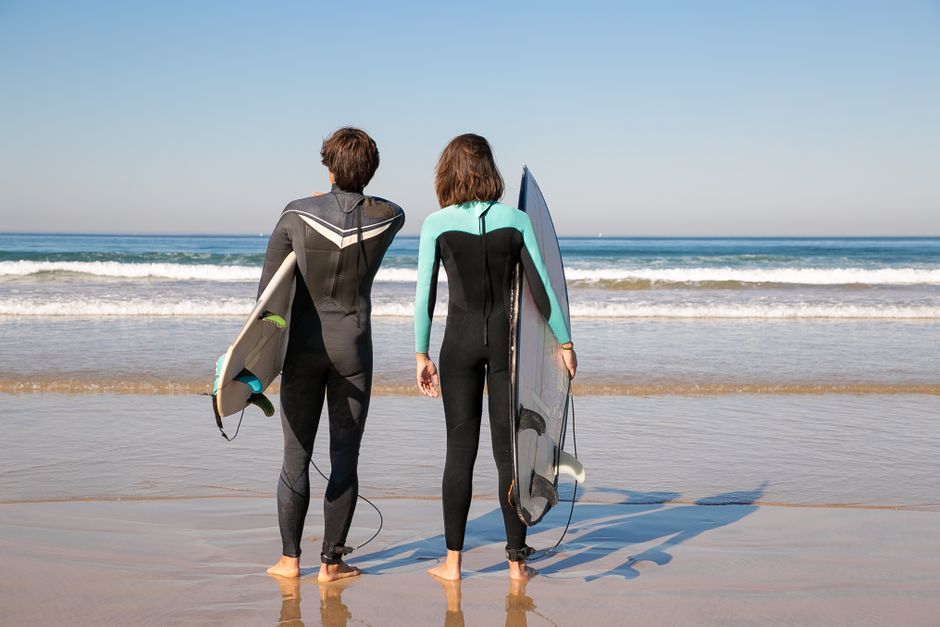 Clase de surf para principiantes con tabla y neopreno en la playa