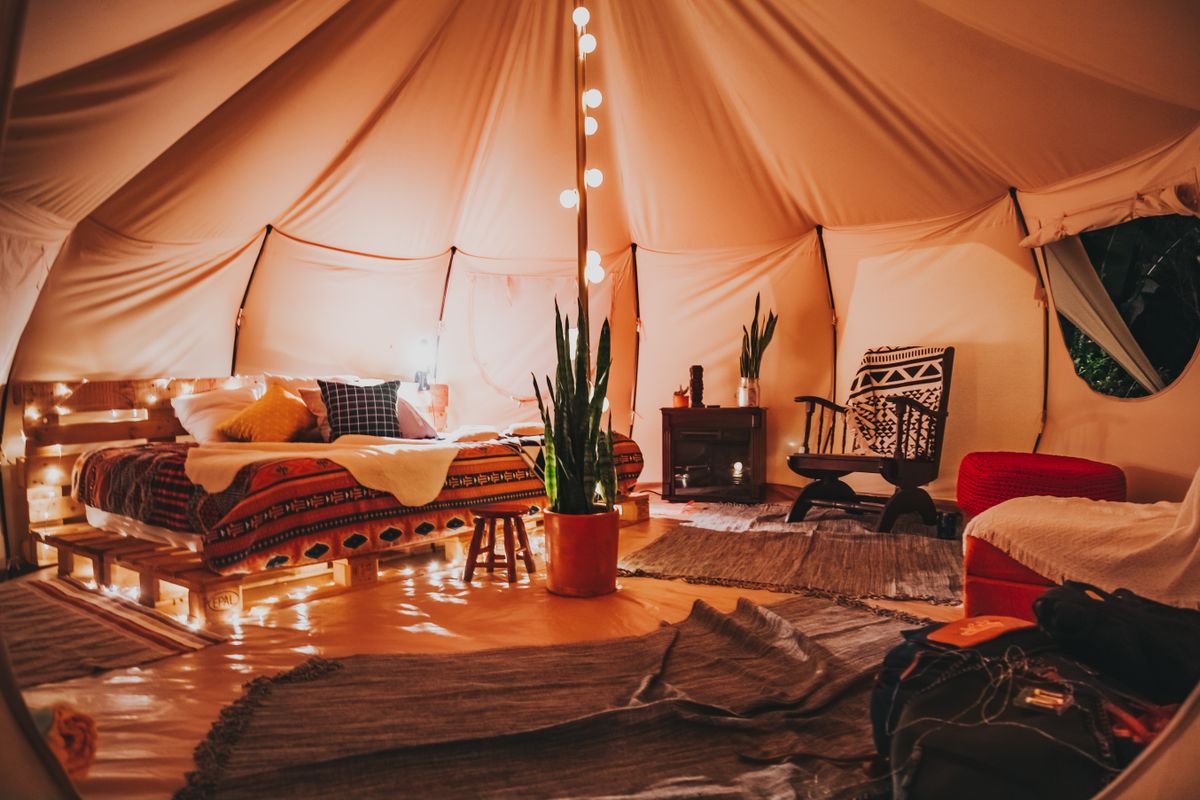 Interior acogedor de una tienda de glamping de lujo con cama y decoración natural