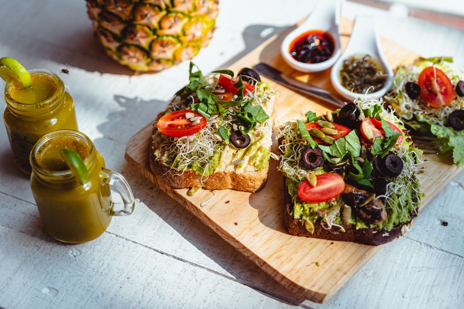 Mesa de brunch con tostas y zumos naturales junto a la playa