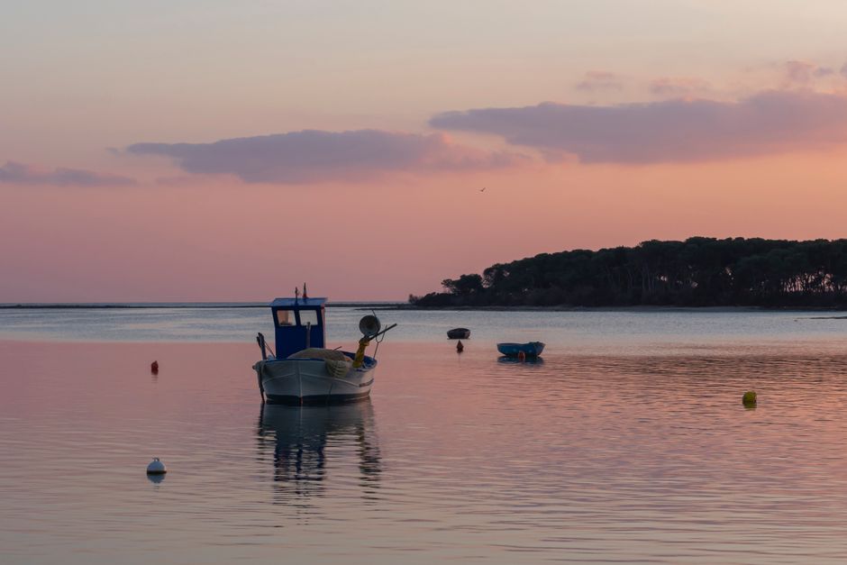 Barco pequeño navegando por la costa al atardecer