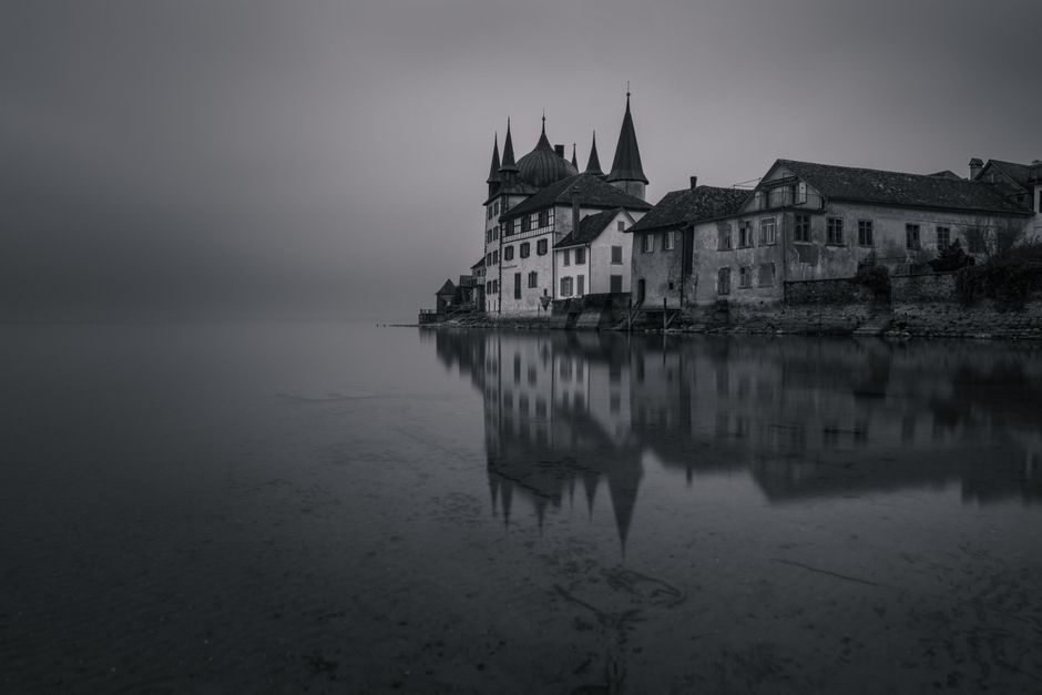 Castillo envuelto en niebla junto a un lago