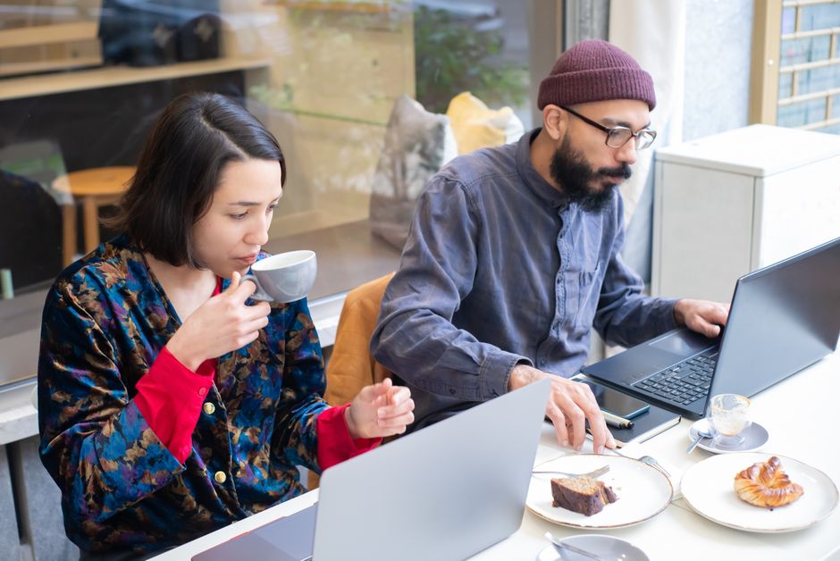 Dos personas trabajando con portátiles en una cafetería