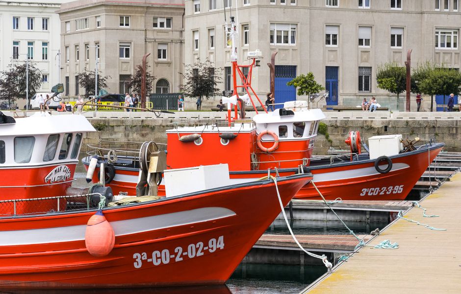 Barcos pesqueros rojos amarrados en un puerto gallego